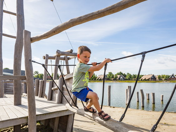 Kind balanseeert over een touwbrug boven het water bij Landal Hof van Saksen