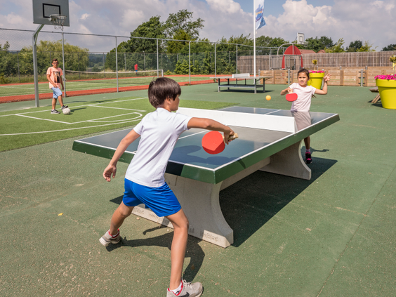 Twee jongens spelen een fanatiek potje tafeltennis op de buitentafeltennistafel op het sportveld van Landal Hoog Vaals.