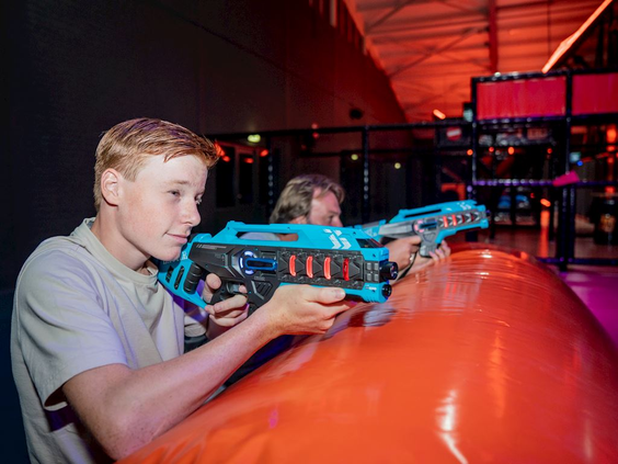 Twee jongens richten geconcentreerd hun lasergun op een doelwit in de spannende lasergame-arena van Landal Hoog Vaals.