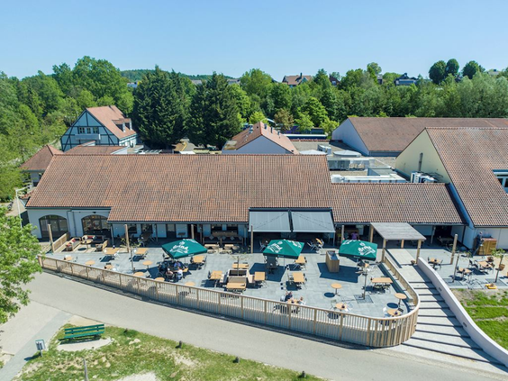 Het zonnige terras met vele zitjes en parasols bij het hoofdgebouw van Landal Hoog Vaals, met uitzicht op het Limburgse landschap.