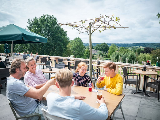 Een gezin geniet van een drankje op het ruime terras van Landal Hoog Vaals, met een prachtig uitzicht over de Limburgse heuvels.
