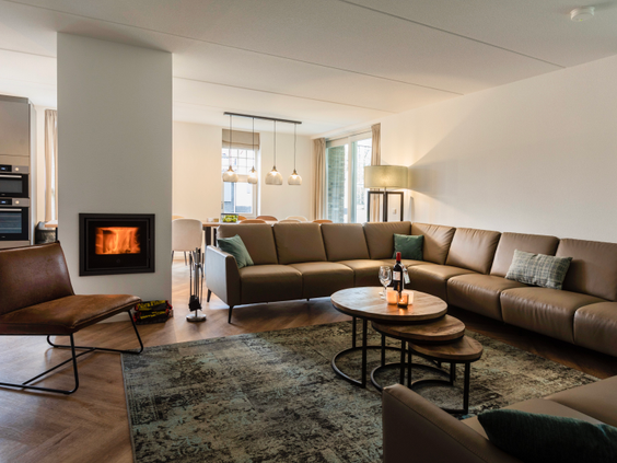 De sfeervolle en ruime woonkamer van een vakantiehuis op Landal Kaatsheuvel, met een grote hoekbank en een gezellige open haard.