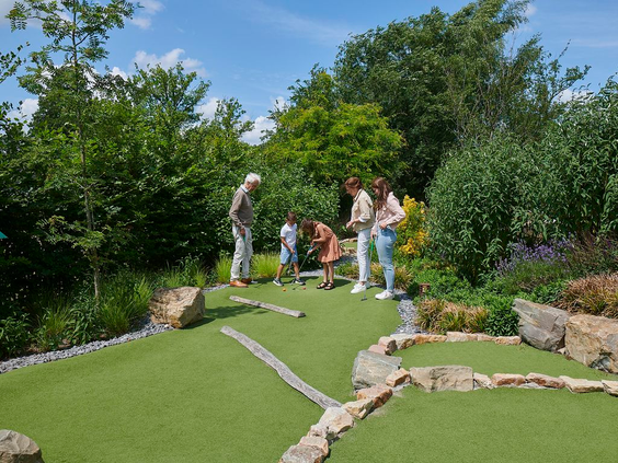 Een gezin speelt een potje midgetgolf op de avontuurlijke golfbaan, gelegen in het groen op Landal Klein Oisterwijk.