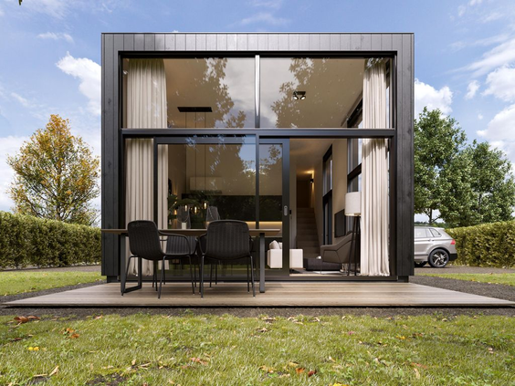 Een moderne, zwarte design vakantiewoning met een groot glazen pui en een terras op een grasveld bij Landal Klein Oisterwijk.