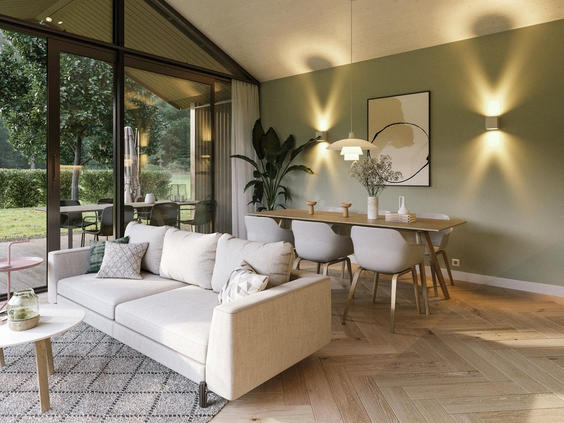 Stijlvol ingerichte, lichte woonkamer van een vakantiewoning op Landal Klein Oisterwijk met een witte bank en uitzicht op het bos.