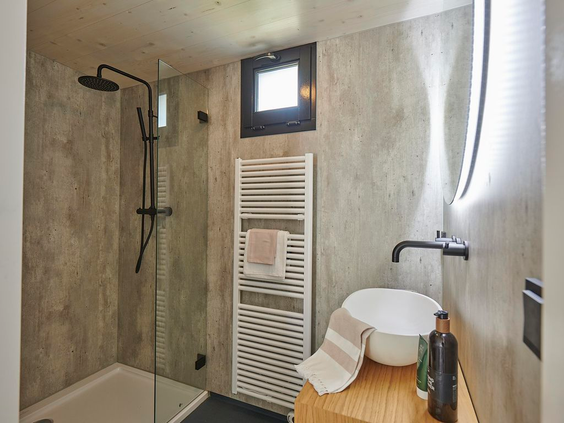 Moderne en luxe badkamer in een vakantiewoning op Landal Klein Oisterwijk, voorzien van een comfortabele inloop regendouche en een wastafel op een houten meubel.