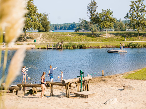 Kinderen spelen met een waterpomp op een houten vlonder bij het zandstrandje aan het Leukermeer op Landal Marina Resort Well.