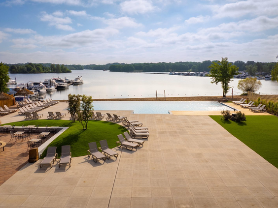 Het luxe zonneterras met ligbedden en een infinity pool, dat prachtig uitkijkt over de jachthaven en het Leukermeer bij Landal Marina Resort Well.