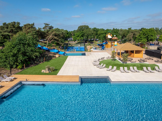 Uitzicht vanaf de rand van de infinity pool op het buitenzwembad, de familieglijbaan en het spraypark bij Landal Marina Resort Well.