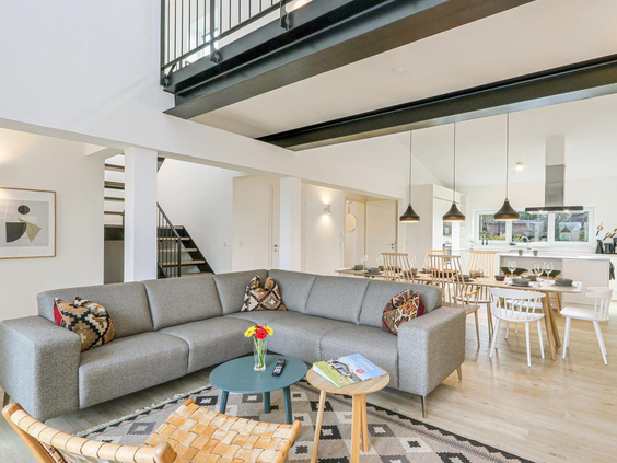 Ruime en moderne woonkamer met grote bank, eettafel en open keuken in een vakantiewoning op Landal Marissa, ideaal voor gezinnen.