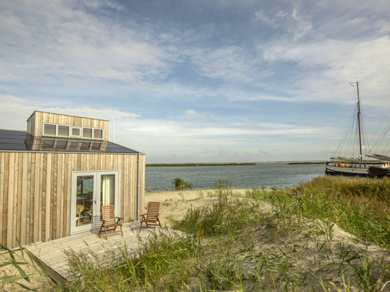 Een duurzaam, houten eilandhuisje van Landal Marker Wadden, gelegen op het strand met uitzicht over het water van het Markermeer.