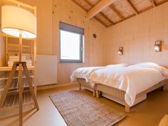 De knusse en sfeervolle houten slaapkamer met twee opgemaakte bedden in een eilandhuisje op Landal Marker Wadden.