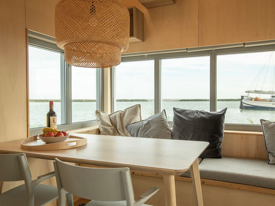 Gezellige eethoek met een vaste bank bij het raam in een eilandhuisje op Landal Marker Wadden, met een panoramisch uitzicht over het water van het Markermeer.