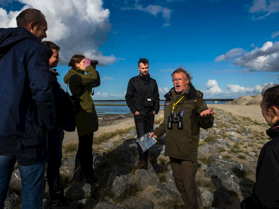 Een boswachter van Natuurmonumenten geeft een rondleiding en uitleg aan een groepje bezoekers op het strand van de Marker Wadden.