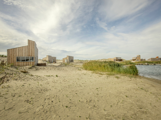 De duurzame, houten eilandhuisjes van Landal Marker Wadden, gelegen in het zand van het havenstrand aan de rand van het Markermeer.