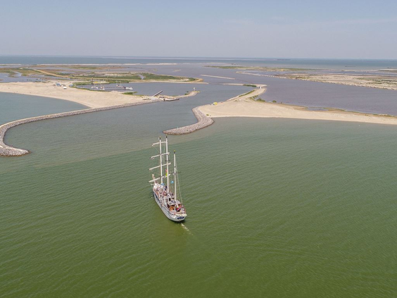 Luchtfoto van het grote zeilschip 'Willem Barentsz' dat vaart tussen de nieuw aangelegde eilanden van de Marker Wadden.