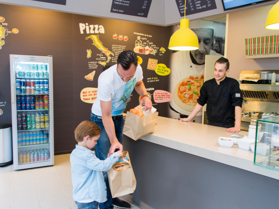 Vader en zoon halen een verse pizza en snacks af bij de snackbar op Landal Miggelenberg.