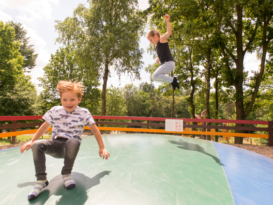 Kinderen springen hoog in de lucht op de grote airtrampoline op Landal Miggelenberg.