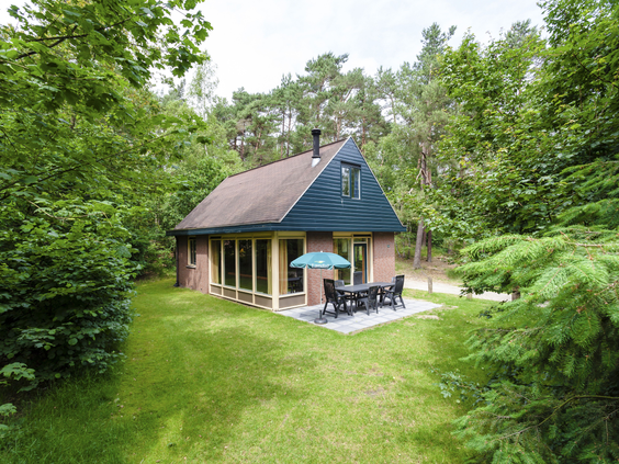 Vrijstaande bungalow met terras, omgeven door een groot grasveld en bomen op Landal Miggelenberg.