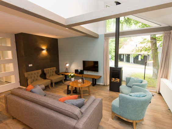 Het moderne en lichte interieur van een luxe, vernieuwde bungalow op Landal Miggelenberg, met een sfeervolle houtkachel.