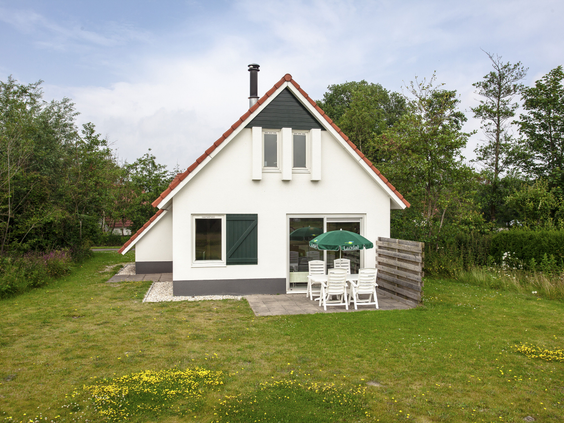 Vrijstaande witte bungalow met een terras en een grote, groene tuin op Landal Natuurdorp Suyderoogh, gelegen bij Nationaal Park Lauwersmeer.