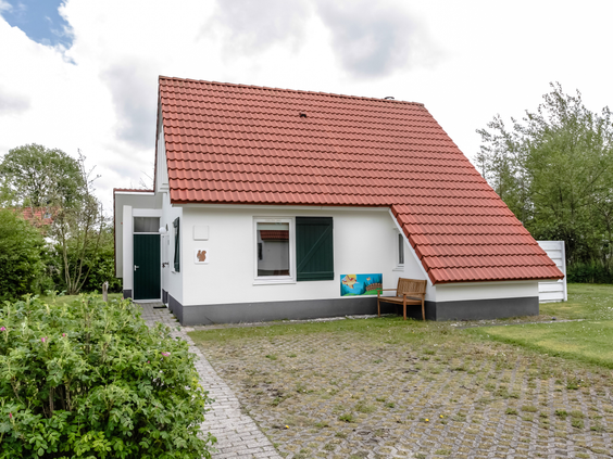 De voorkant van een comfortabele, witte vakantiebungalow met rode dakpannen op Landal Natuurdorp Suyderoogh.