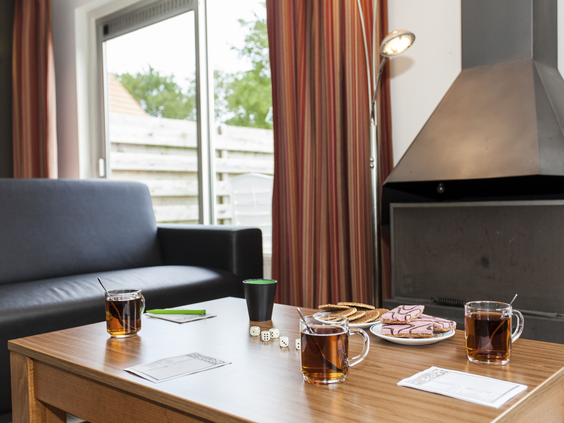 Een knusse zithoek met een salontafel vol met thee, koekjes en spelletjes in een bungalow op Landal Natuurdorp Suyderoogh.