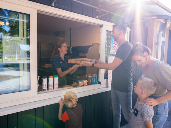 Gezin haalt verse pizza's en snacks af bij het afhaalloket van de snackbar op Landal Orveltermarke.