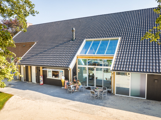 Het moderne centrumgebouw van Landal Orveltermarke met een groot glazen entree en een terras.