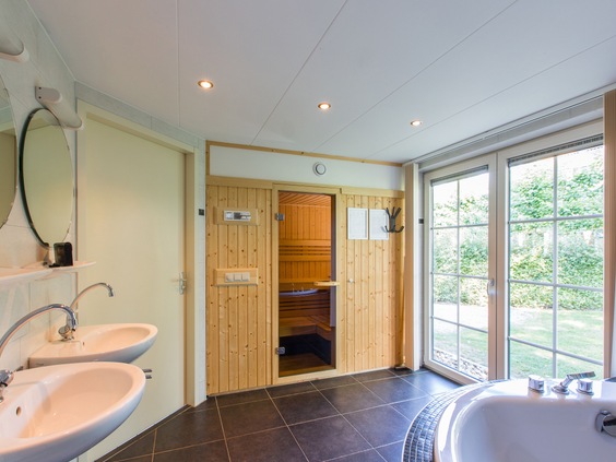 Luxe badkamer in een bungalow op Landal Orveltermarke, voorzien van een ligbad en een privé sauna voor extra ontspanning.