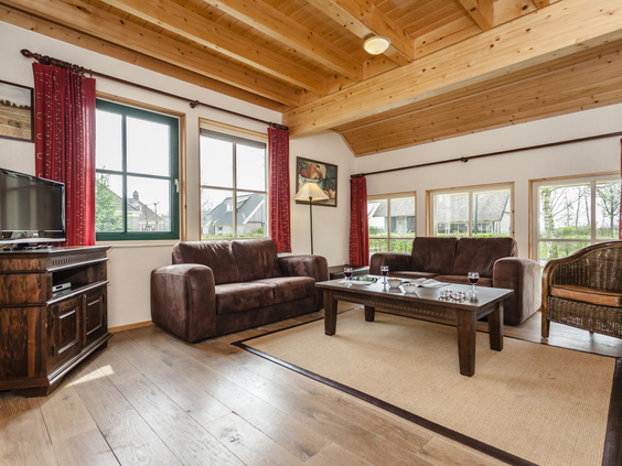Gezellige woonkamer met houten balkenplafond en comfortabele banken in een boerderijbungalow op Landal Orveltermarke.