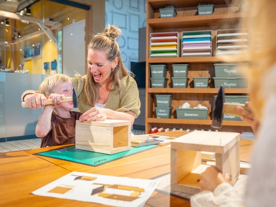 Kind en moeder timmeren samen een houten vogelhuisje in de creatieve werkplaats van Landal Orveltermarke.