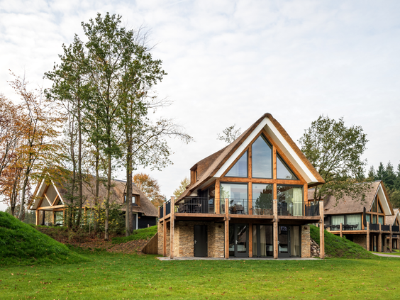 Een luxe houten vakantievilla met grote ramen op Landal Puur Exloo in Drenthe, prachtig gelegen in het groene landschap van de Hondsrug.