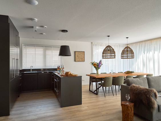 Ruime en sfeervol ingerichte woonkamer van een vakantievilla op Landal Puur Exloo, met een grote zithoek en eettafel.