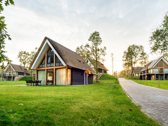 Luxe houten vakantievilla op Landal Puur Exloo bij zonsondergang, prachtig gelegen in de groene, bosrijke omgeving van de Hondsrug.