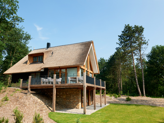 Een luxe houten vakantievilla met rieten dak op Landal Puur Exloo, gelegen op een heuvel midden in de bossen van Drenthe.