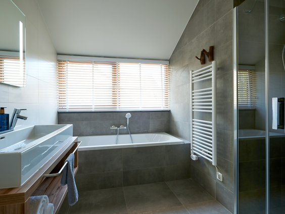 Moderne en luxe badkamer in een vakantievilla op Landal Puur Exloo, met een groot ligbad, dubbele wastafel en een strak design.