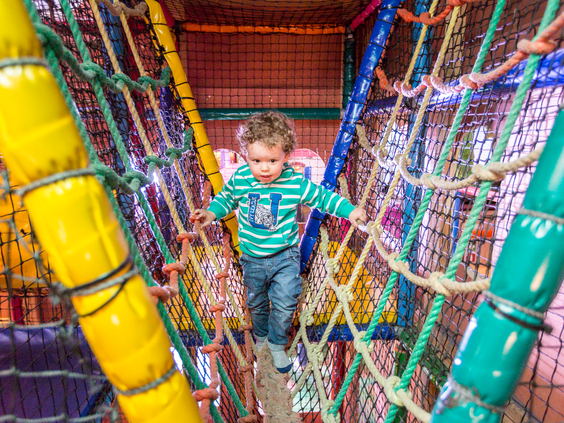 Een jongen balanceert over een touwbrug in de avontuurlijke en kleurrijke binnenspeeltuin van Landal Rabbit Hill.
