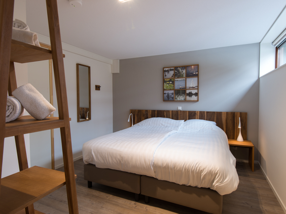 Een modern ingerichte slaapkamer in een waterwoning op Landal Reeuwijkse Plassen, met een opgemaakt tweepersoonsbed en sfeervolle verlichting.