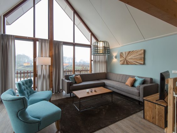 Het lichte en sfeervolle interieur van een waterwoning op Landal Reeuwijkse Plassen, met hoge ramen die een prachtig uitzicht bieden over het water.