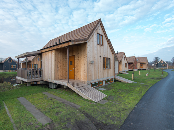 De voorkant van een duurzame, houten waterwoning op Landal Reeuwijkse Plassen, gezien vanaf de landzijde met een loopplank naar de voordeur.