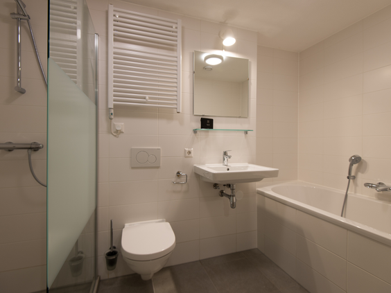 Nette, moderne badkamer in een waterwoning op Landal Reeuwijkse Plassen, voorzien van een ligbad, inloopdouche, wastafel en toilet.