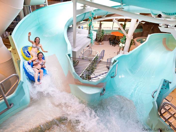 Twee kinderen roetsjen met een opblaasband van de brede waterglijbaan in het zwemparadijs van Landal Salztal Paradies.