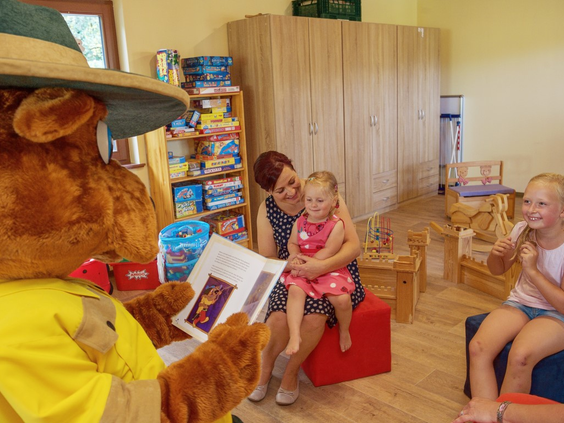 Landal mascotte Bollo de Beer leest een verhaaltje voor aan jonge kinderen in de Bollo Club van Salztal Paradies.