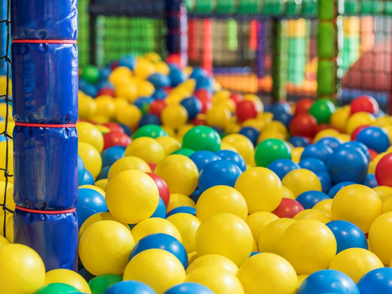 Een kleurrijke ballenbak in de indoorspeeltuin van Landal Salztal Paradies, vol met gele, blauwe en groene ballen.