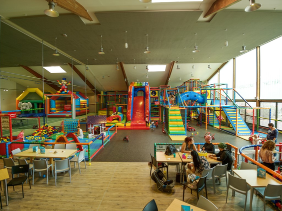 Overzicht van de grote, kleurrijke indoorspeeltuin van Landal Salztal Paradies, met klimrekken, glijbanen en speeltoestellen.