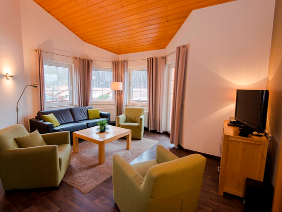 Gezellige woonkamer van een vakantiehuis bij Landal Salztal Paradies met een comfortabele zithoek en houten plafond.