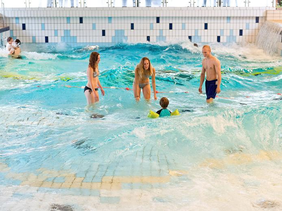 Een gezin met twee kinderen heeft plezier in het golfslagbad van het zwemparadijs bij Landal Salztal Paradies.