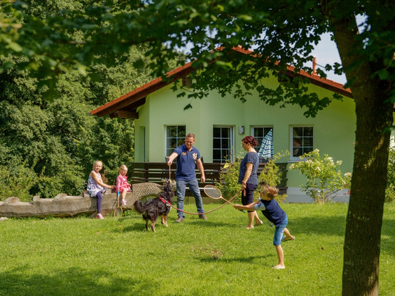 Gezin speelt en maakt een radslag in de tuin voor hun vakantiewoning op vakantiepark Landal Salztal Paradies.