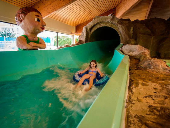 Meisje komt met een opblaasband uit de donkere tunnel van de waterglijbaan in het zwembad van Landal Salztal Paradies.